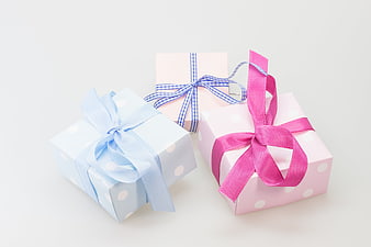 Three pastel polka dot gift boxes with ribbons on white background