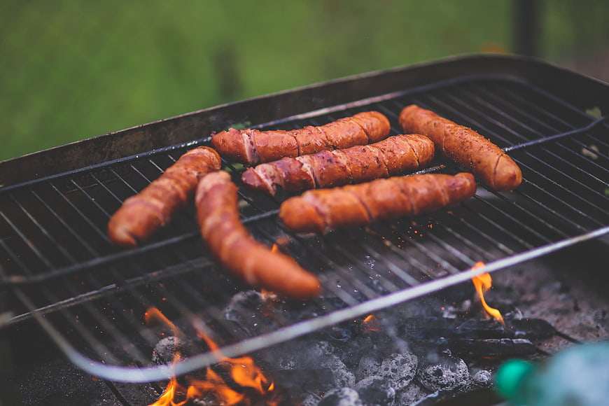 Grilled sausages cooking on charcoal barbecue grill