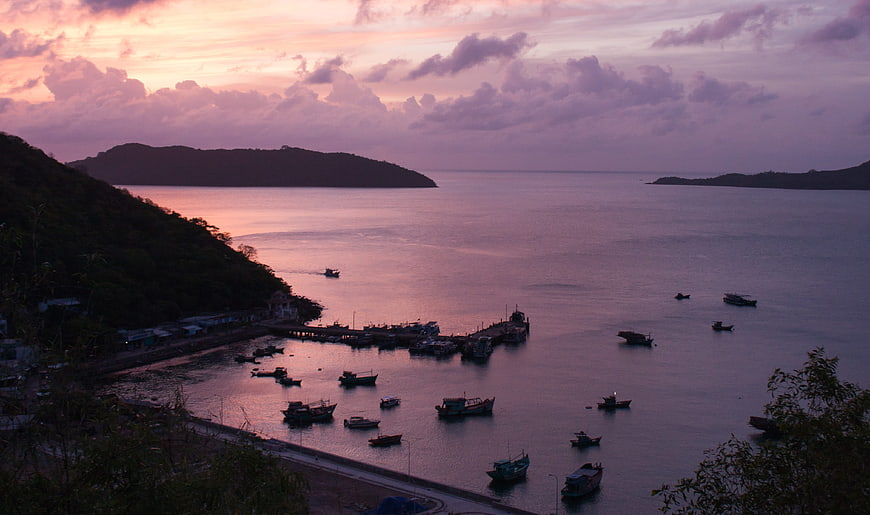 Serene coastal harbor at sunset with fishing boats and purple sky