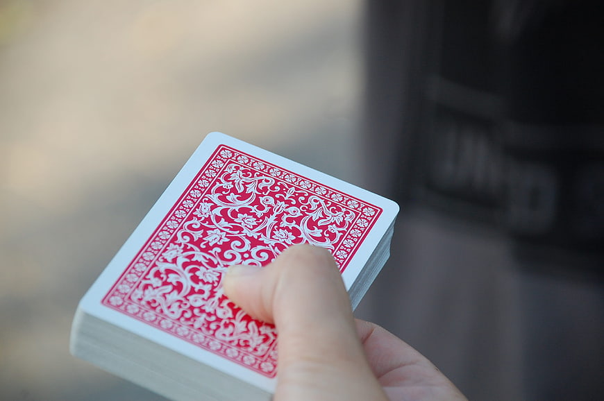 Hand holding deck of red playing cards close up