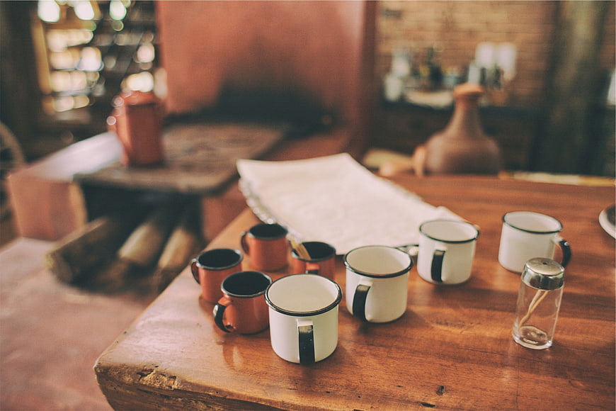 Rustic enamel mugs on a wooden table in a cozy cafe