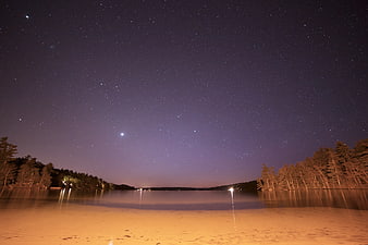 Starry Night Sky Over Lake With Sandy Beach