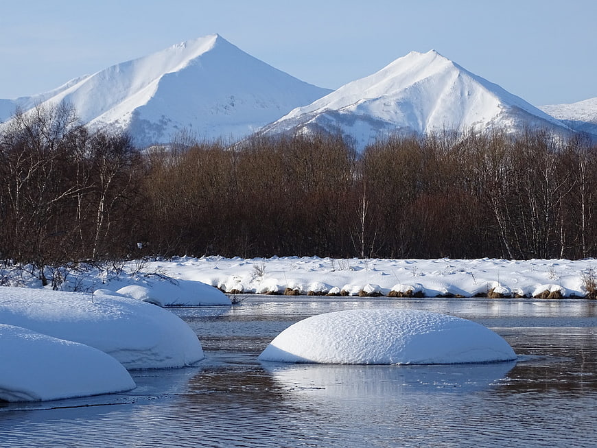 Snow-covered mountains and river in winter landscape