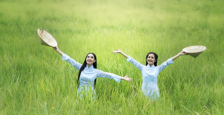 Two Vietnamese women in ao dai celebrating in rice field