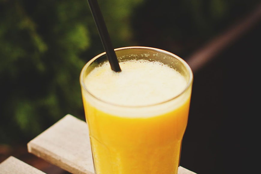 Fresh Orange Juice in Glass with Black Straw on Wooden Table
