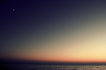 Crescent Moon Over Calm Ocean at Twilight