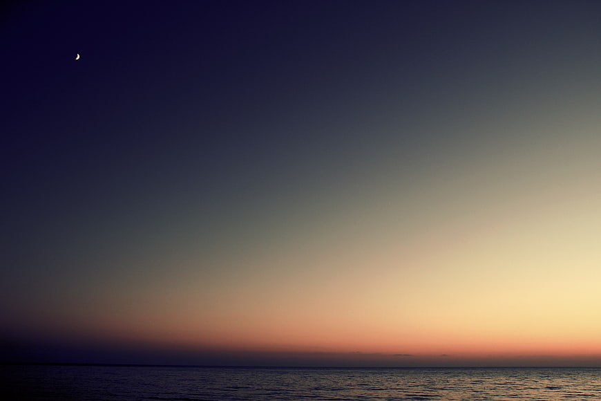 Crescent Moon Over Calm Ocean at Twilight