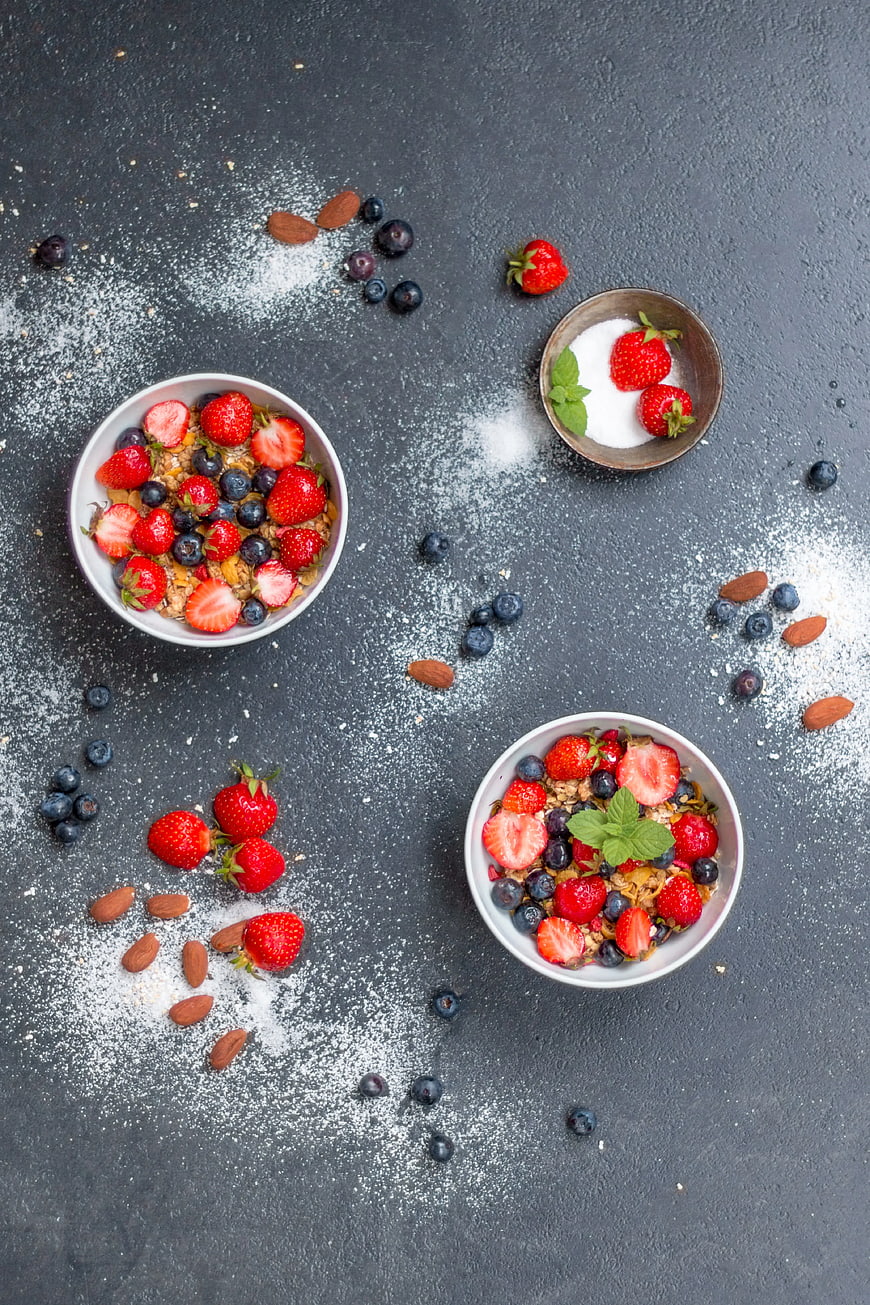 Overhead view of healthy breakfast bowls with berries and granola
