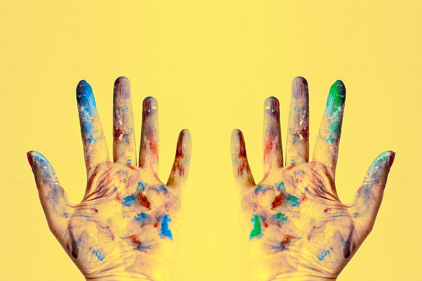 Colorful Painted Hands on Yellow Background