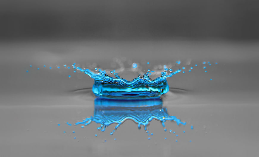Blue liquid splash crown with reflection on gray background
