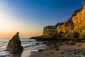 Golden Sunrise on Rocky Coastal Cliffs and Ocean Beach