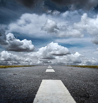 Low angle view of empty asphalt road with dramatic clouds