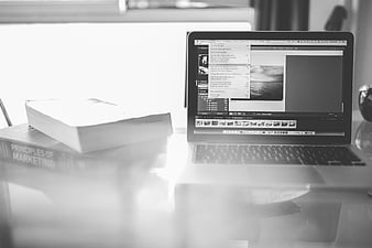 Black and white laptop with marketing book on desk
