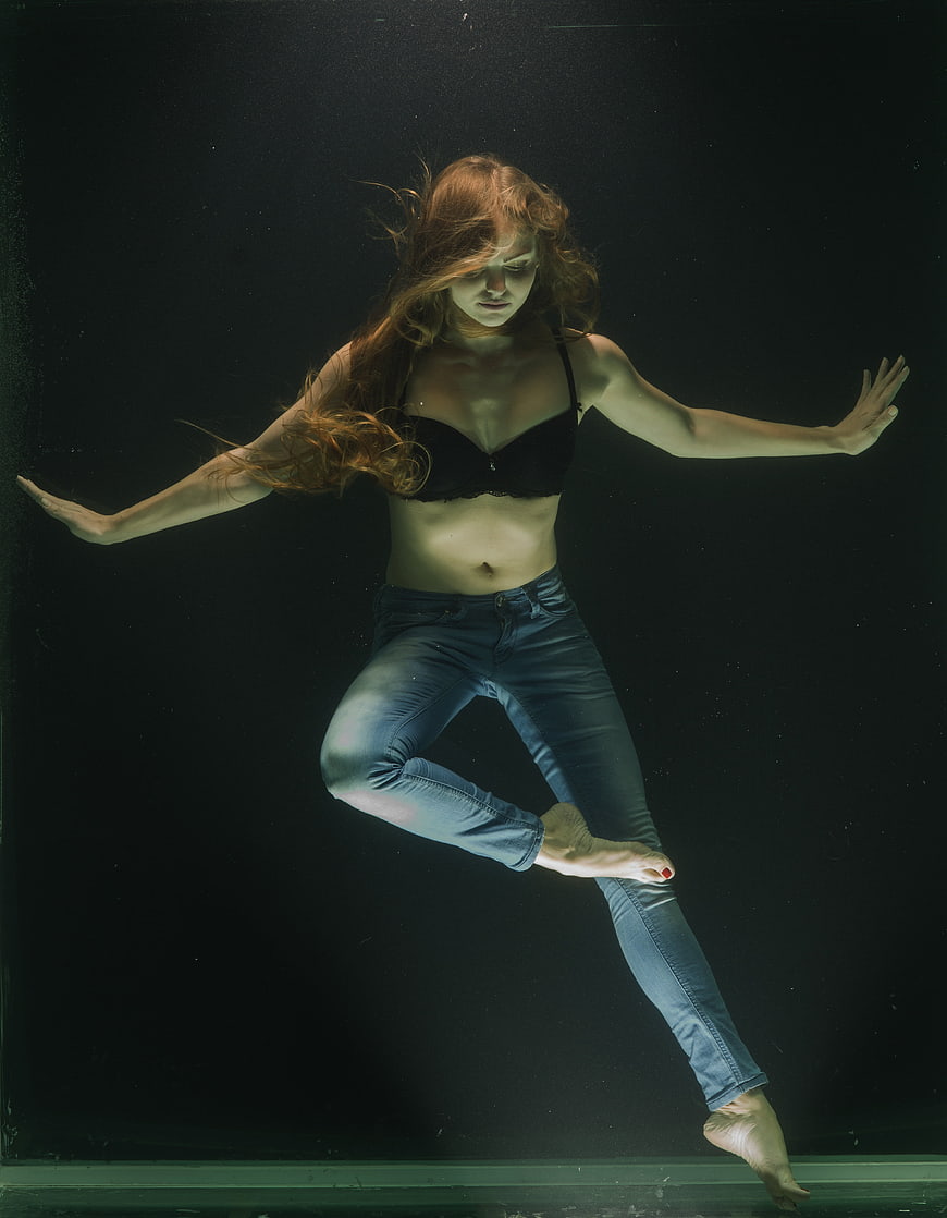 Underwater woman in jeans and black bra floating
