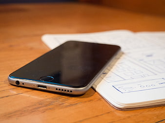 Smartphone on Notebook with Wireframe Sketches on Wooden Desk