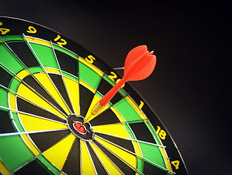 Red dart hitting bullseye on dartboard close up