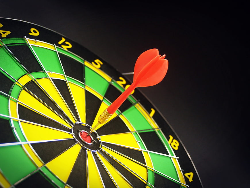 Red dart hitting bullseye on dartboard close up