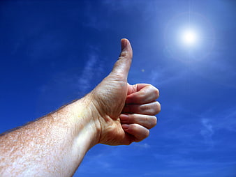 Hand Giving Thumbs Up Against Blue Sky