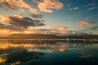Golden sunset over glacial lagoon with icebergs and mountain reflection