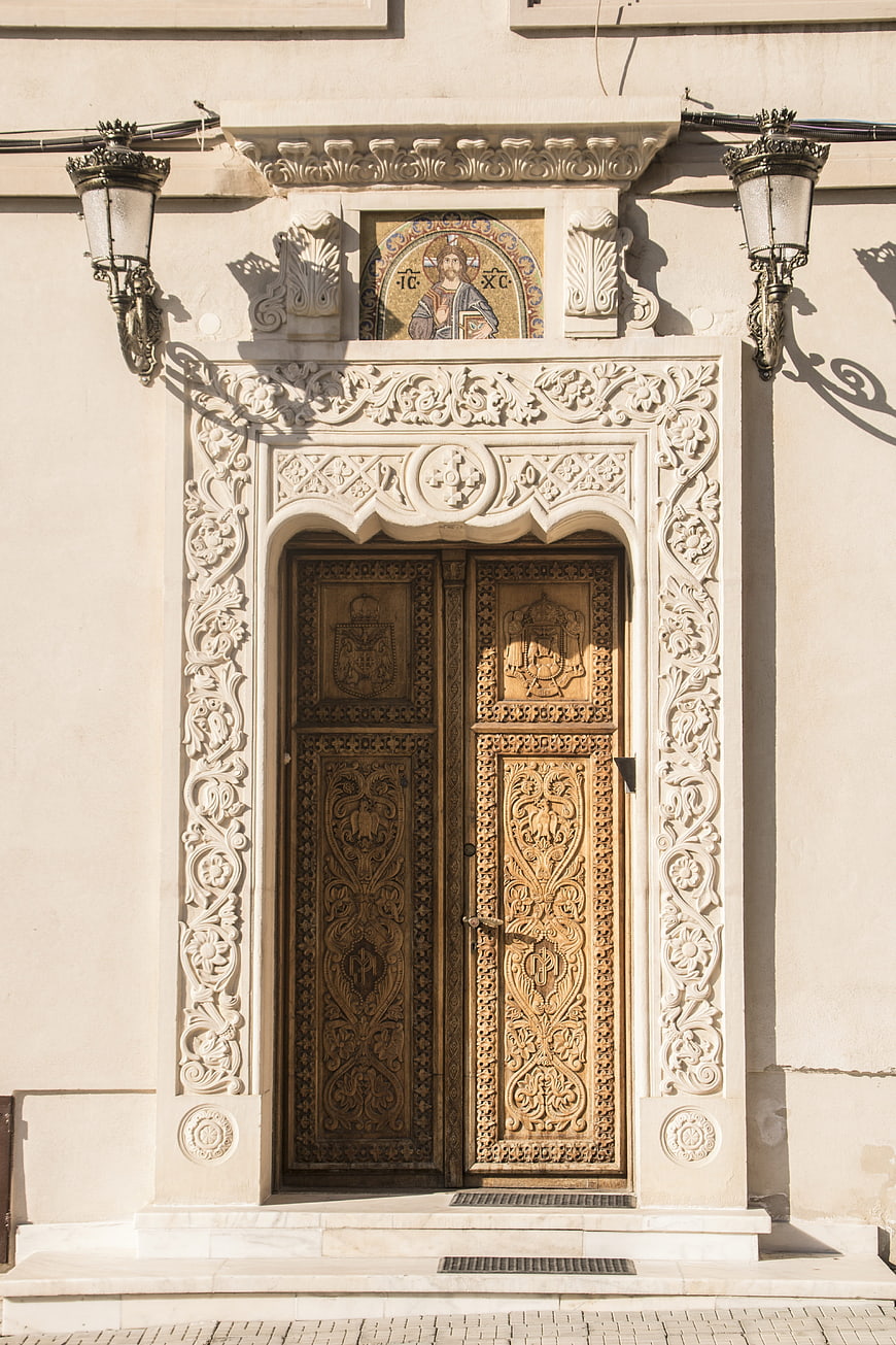 Ornate wooden church door with religious mosaic and stone carvings