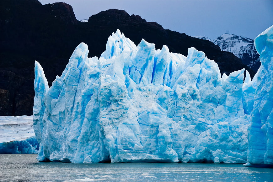 Massive Blue Glacier Iceberg Floating in Water