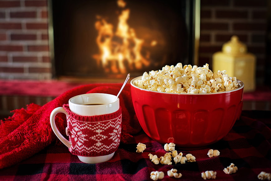 Cozy Winter Scene with Popcorn and Hot Coffee by Fireplace