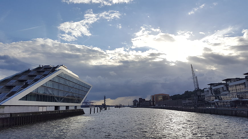 Modern angular building on riverbank with dramatic sky