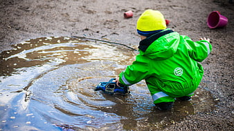 Child playing with toy car in muddy puddle outdoors