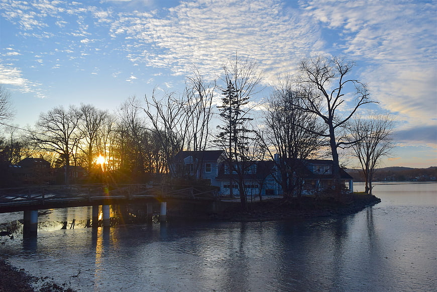 Sunset over a lake with a house and bare trees in winter