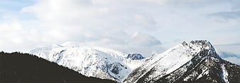 Snow-Covered Mountain Peaks Under Cloudy Sky