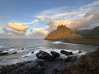 Dramatic coastal landscape with rocky cliffs and ocean waves at sunset