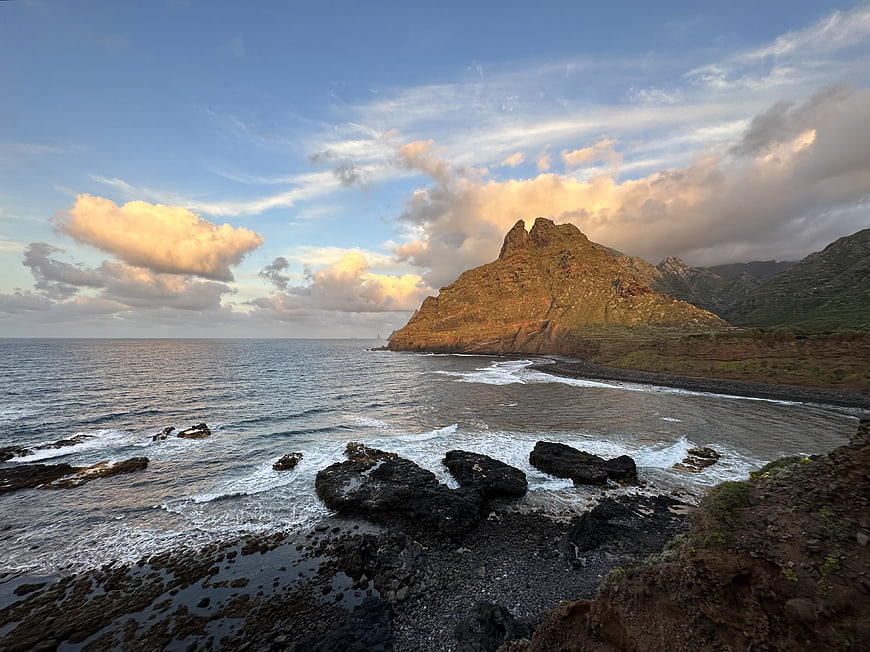 Dramatic coastal landscape with rocky cliffs and ocean waves at sunset