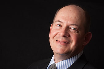 Professional corporate headshot of a smiling businessman in a suit