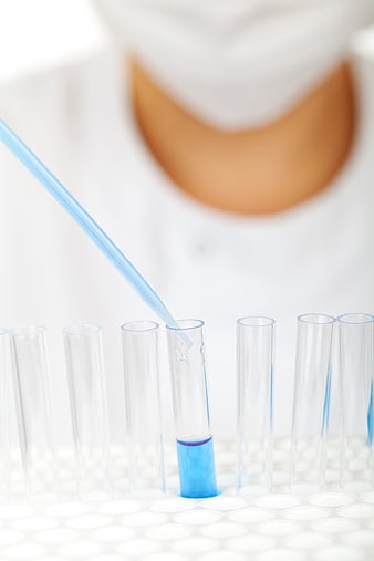 Scientist using pipette to fill test tube with blue liquid