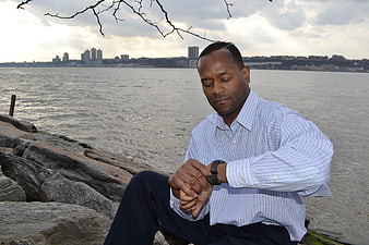 Businessman Checking Watch by River with City Skyline