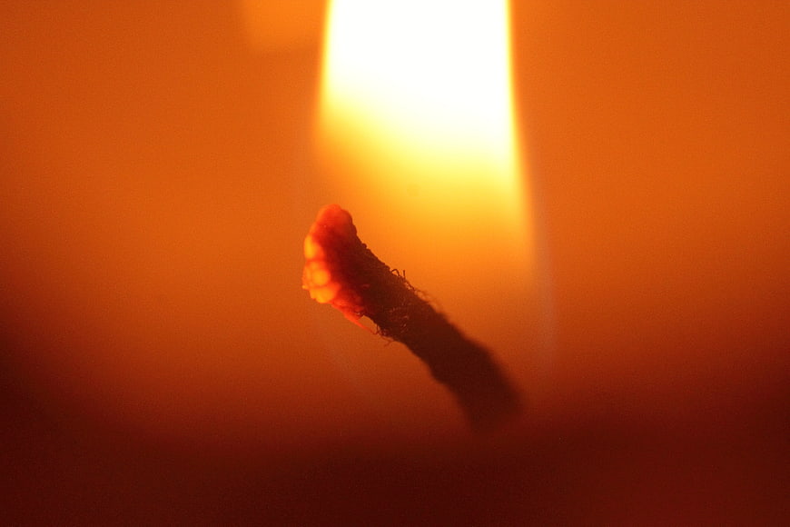 Close-up of burning candle wick with warm orange glow