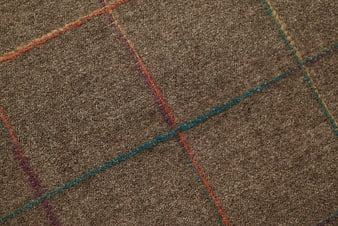 Close-up of brown woven fabric with colorful geometric stitching pattern