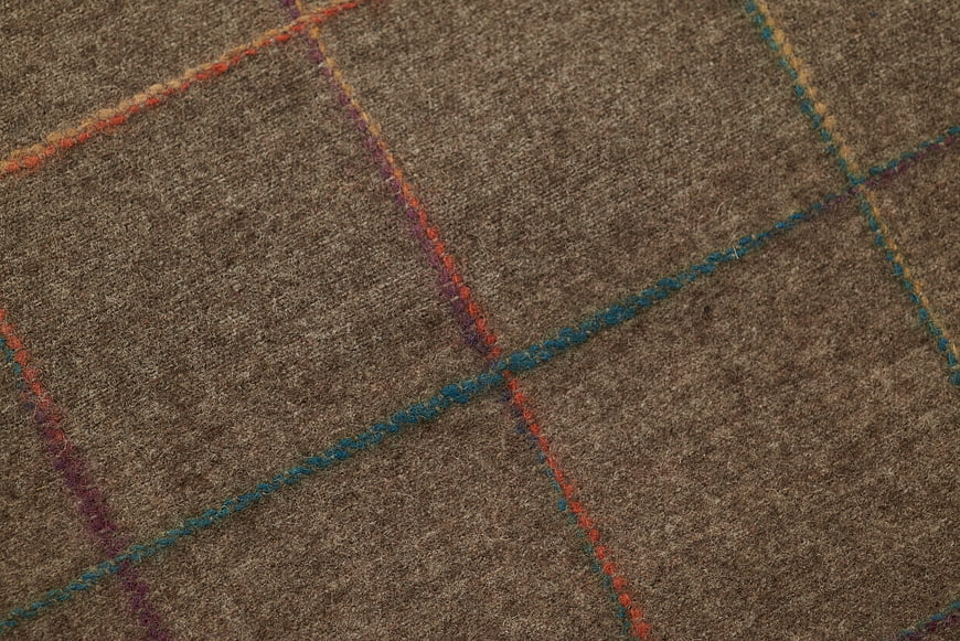 Close-up of brown woven fabric with colorful geometric stitching pattern