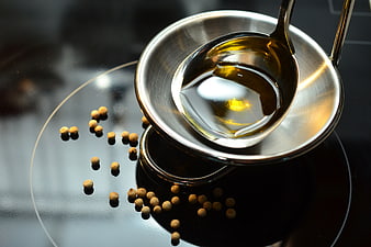 Olive Oil in Spoon with White Peppercorns on Stove