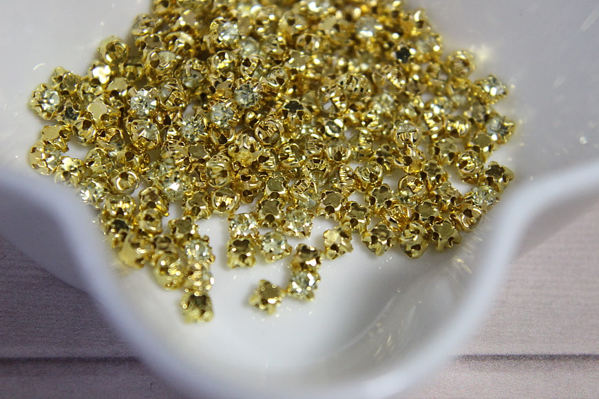 Close-up of gold glass beads in a white ceramic dish