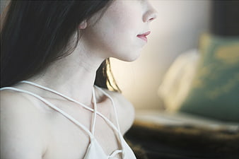 Close-up profile of a woman in a white strappy top