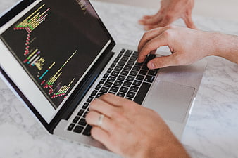 Hands typing code on laptop screen