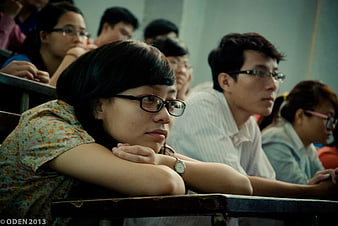 Asian female student resting chin on desk in classroom
