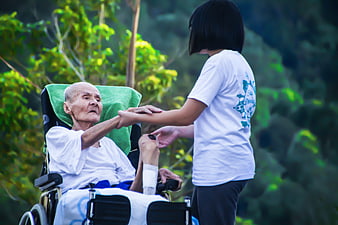 Elderly man in wheelchair receiving physical therapy outdoors