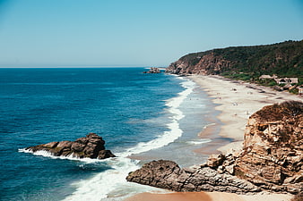 Scenic coastal beach with rocky cliffs and turquoise ocean waves