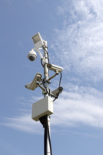 CCTV surveillance cameras on pole against blue sky