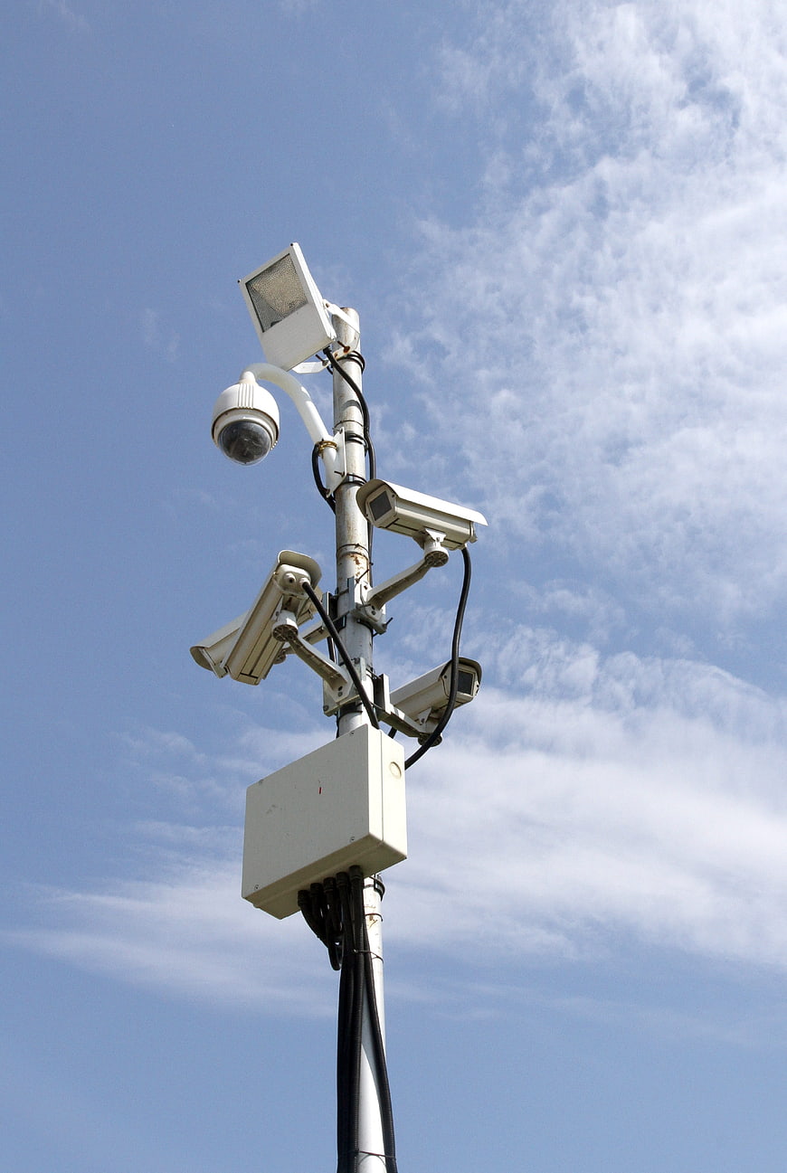 CCTV surveillance cameras on pole against blue sky