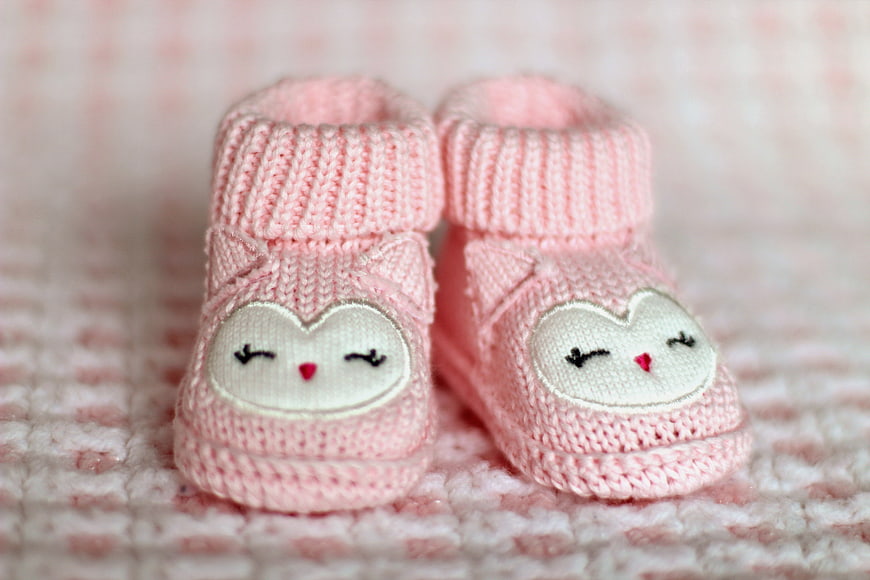 Cute pink knitted baby booties with cat face design