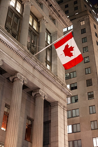Canadian Flag Flying on Classical Building at Night