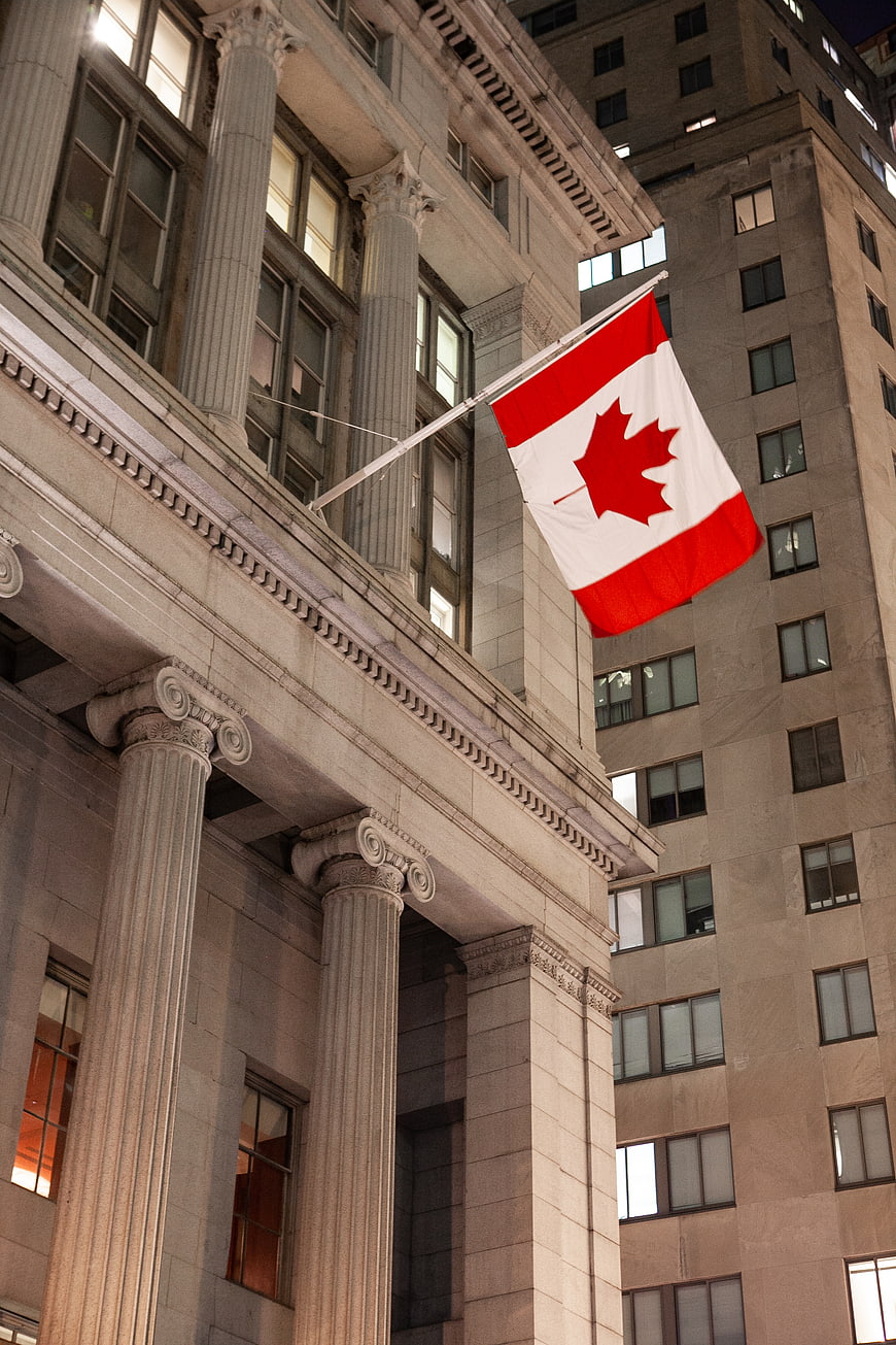 Canadian Flag Flying on Classical Building at Night
